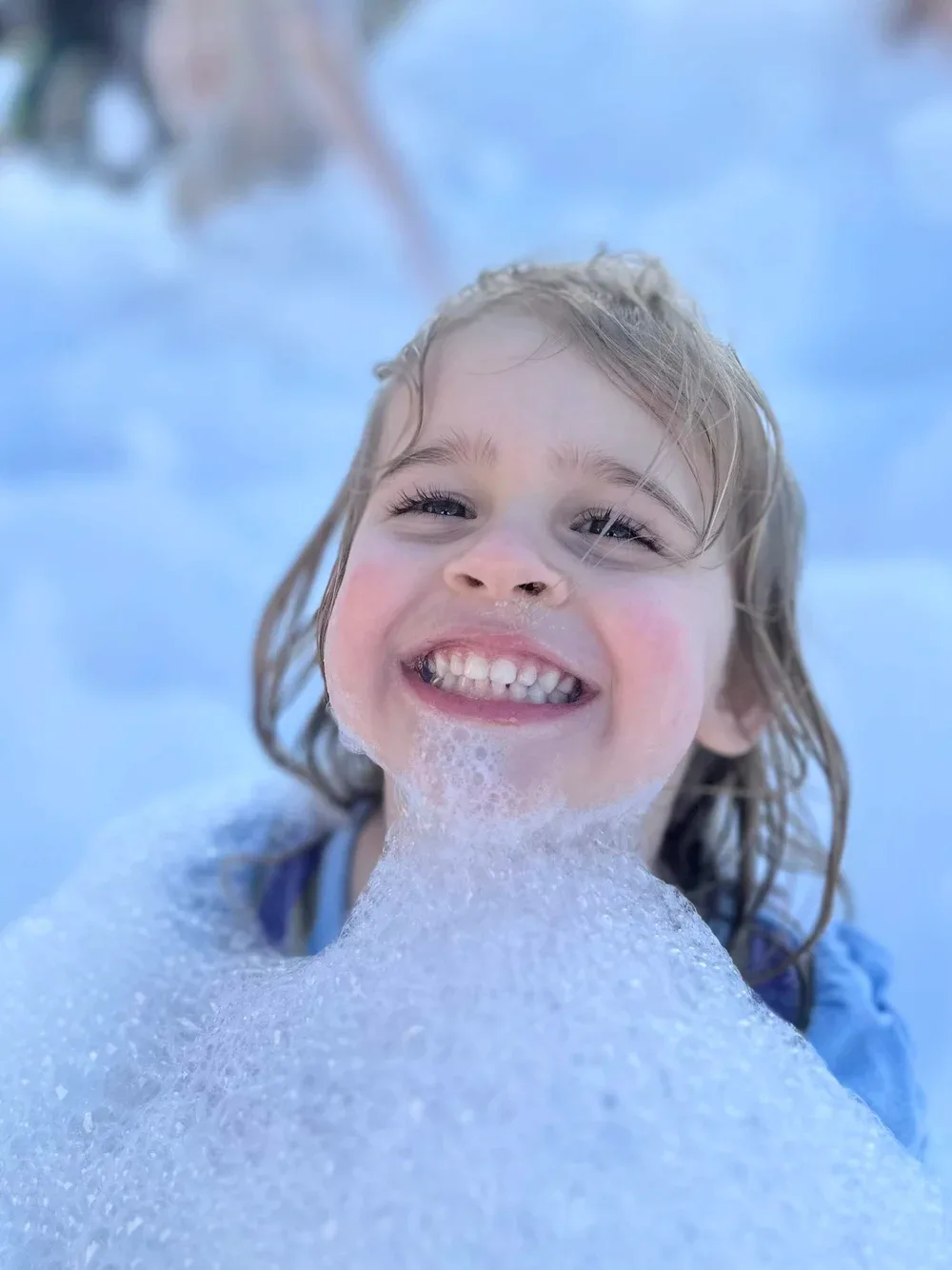 Smiling child up to her chin in foam