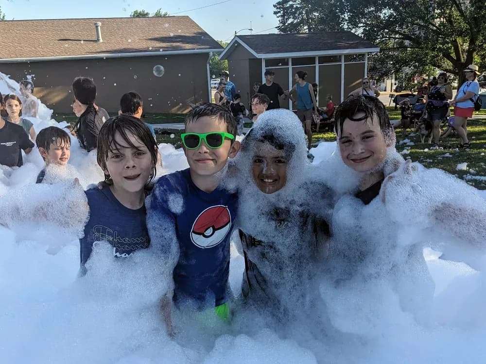 Kids grinning in a backyard full of foam